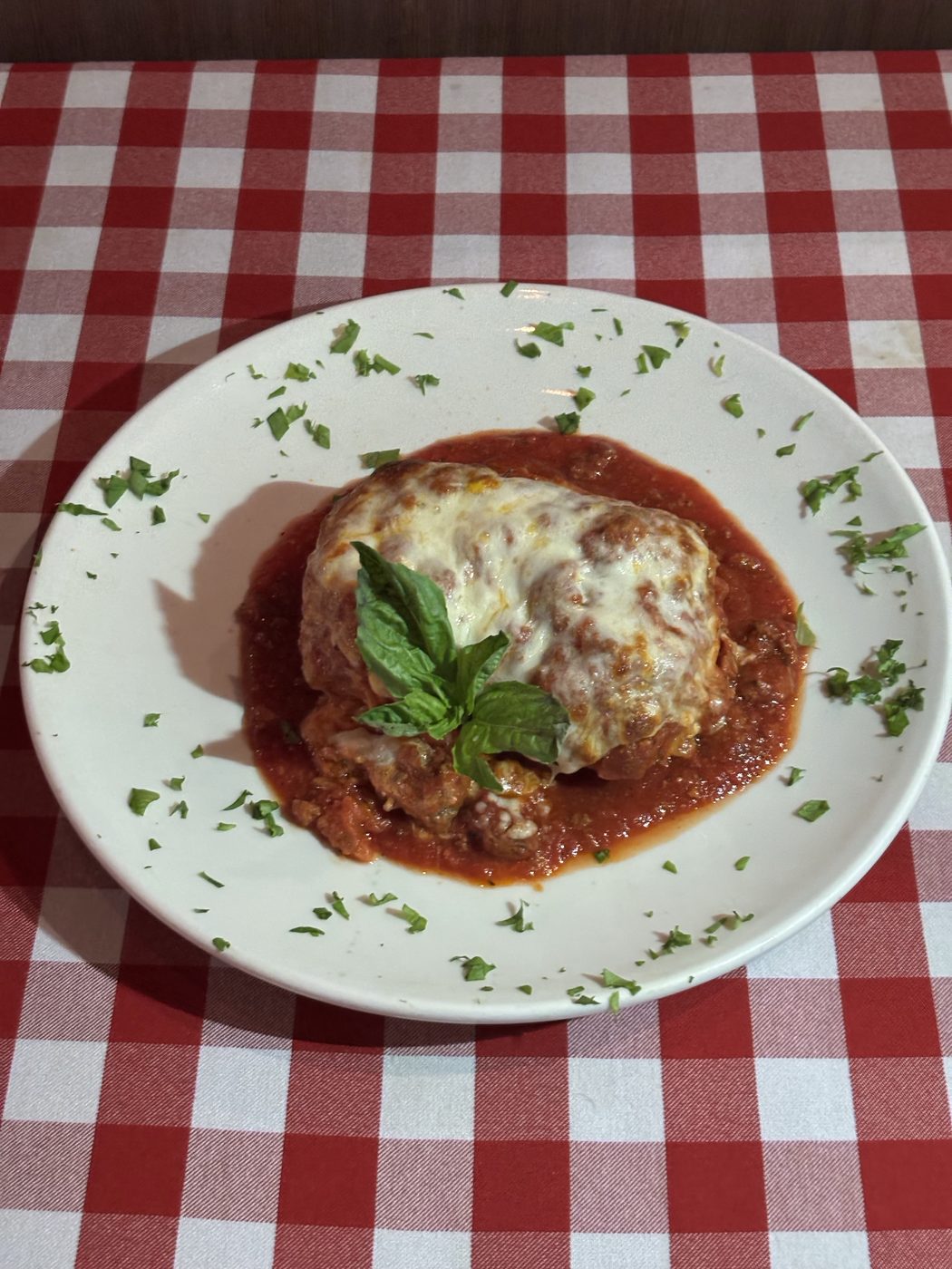Baked lasagna topped with melted cheese and fresh basil